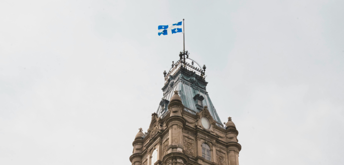 Photo de la tour du Parlement du Québec, surmontée du drapeau de la province. 