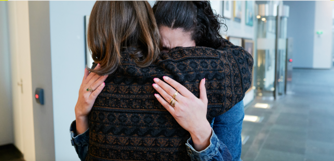 Deux femmes se tiennent dans leurs bras en pleurant.
