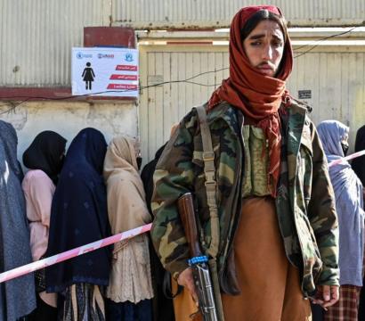 Des femmes voilées sont en arrière-plan, derrière un homme afghan armé